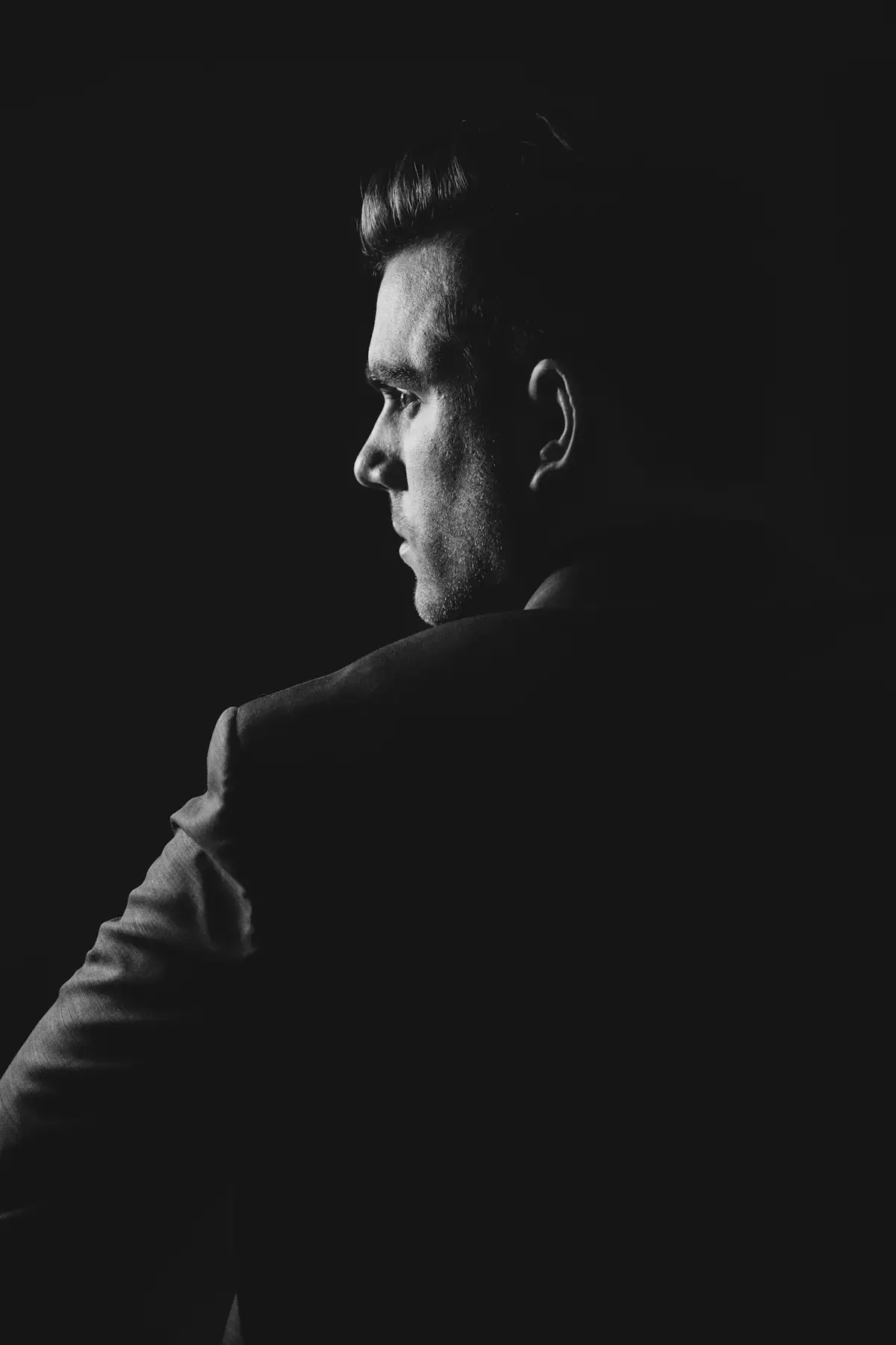 A man in a dark suit, in profile, black and white